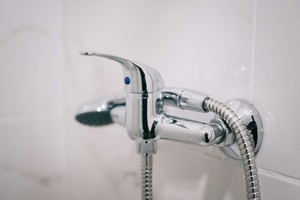 A detailed view of a sleek chrome shower faucet in a clean bathroom setting.